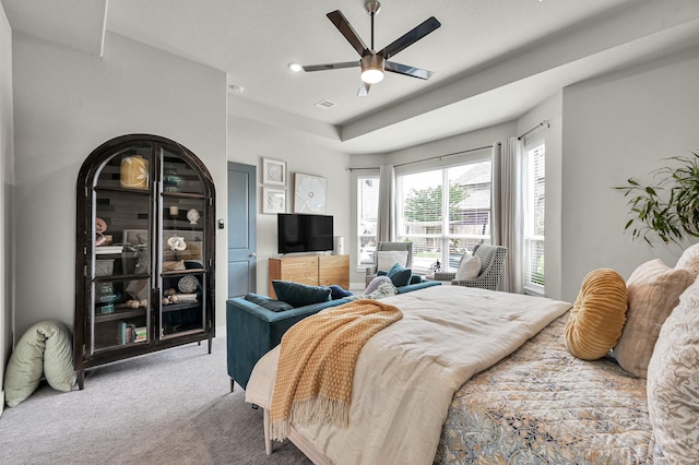 bedroom featuring visible vents, carpet flooring, a raised ceiling, and ceiling fan