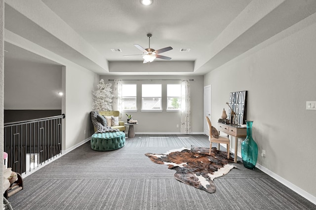 sitting room featuring a raised ceiling, ceiling fan, carpet, and baseboards