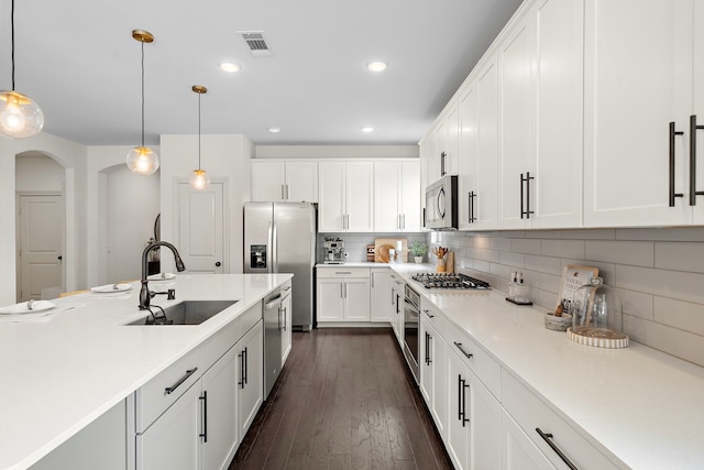 kitchen featuring visible vents, dark wood-style flooring, arched walkways, a sink, and appliances with stainless steel finishes