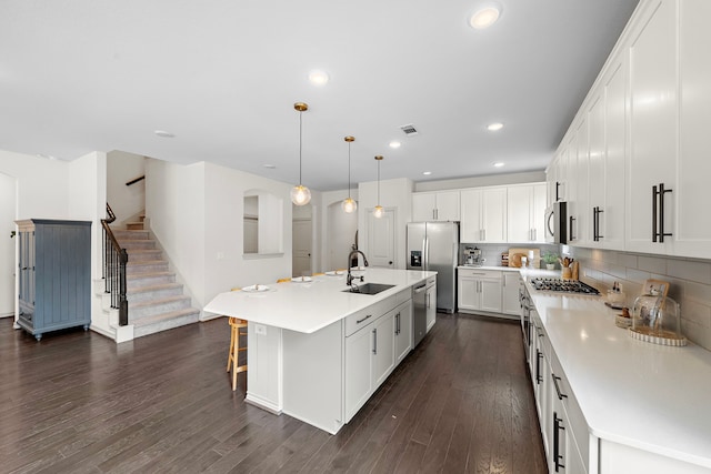 kitchen featuring decorative backsplash, appliances with stainless steel finishes, dark wood finished floors, a sink, and white cabinets
