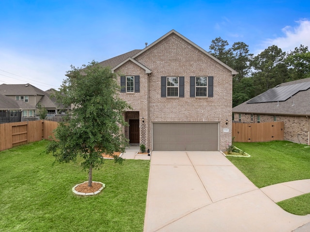 traditional-style house featuring fence, a front yard, brick siding, concrete driveway, and an attached garage