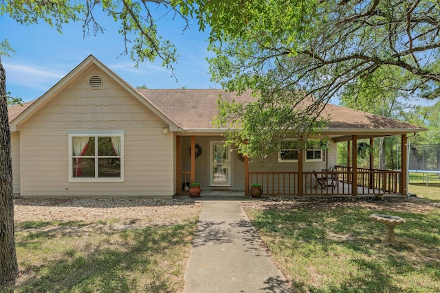single story home featuring a trampoline, roof with shingles, and a front lawn