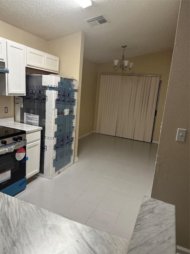kitchen featuring white cabinets, range, a chandelier, and visible vents