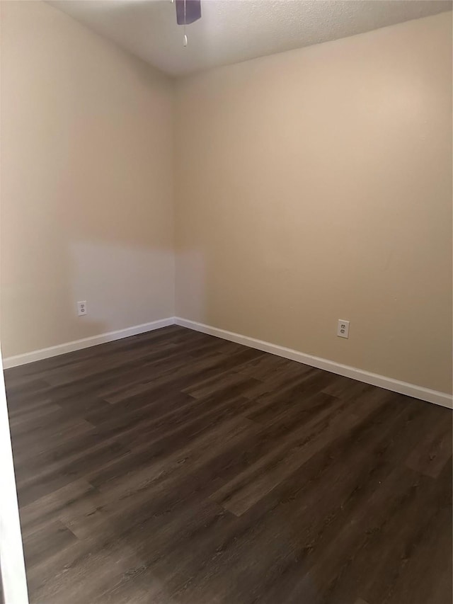 unfurnished room featuring baseboards, a ceiling fan, and dark wood-type flooring