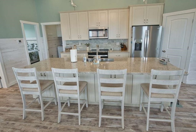 517 Private Road 675, Sargent, TX 77414 - kitchen featuring light stone counters, light wood-style floors, stainless steel appliances, decorative backsplash, and a large island with sink