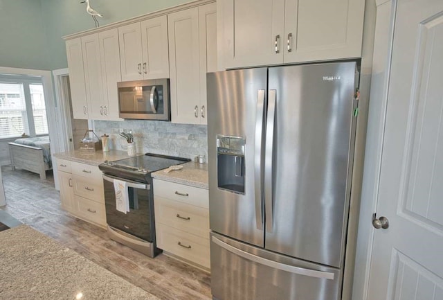 517 Private Road 675, Sargent, TX 77414 - kitchen with appliances with stainless steel finishes, tasteful backsplash, light wood-style flooring, and light stone counters