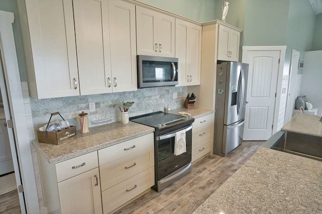 517 Private Road 675, Sargent, TX 77414 - kitchen featuring decorative backsplash, light wood-type flooring, white cabinets, light stone counters, and appliances with stainless steel finishes