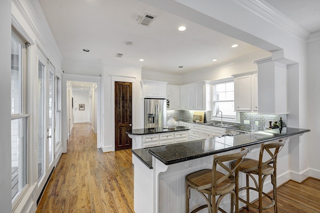 806 Waverly St, Houston, TX 77007 - kitchen with tasteful backsplash, stainless steel fridge with ice dispenser, white cabinetry, a kitchen bar, and visible vents