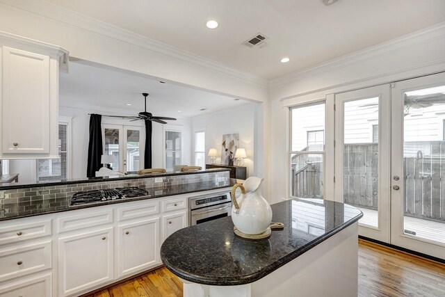 806 Waverly St, Houston, TX 77007 - kitchen with visible vents, dark stone counters, white cabinets, light wood finished floors, and appliances with stainless steel finishes