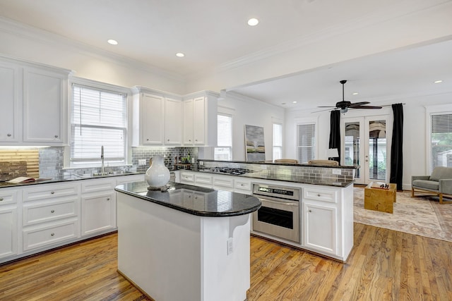 806 Waverly St, Houston, TX 77007 - kitchen with a sink, stainless steel oven, a peninsula, open floor plan, and white cabinetry