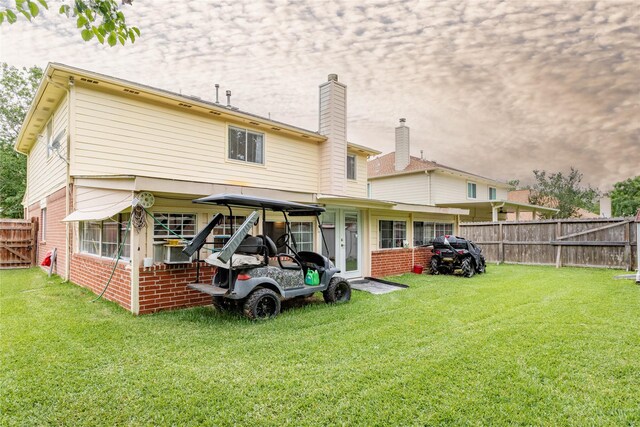 back of property with brick siding, a lawn, fence, and french doors