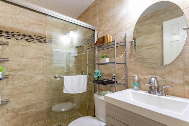 bathroom featuring vanity, a stall shower, toilet, and tile walls