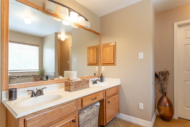 bathroom with double vanity, a sink, and baseboards