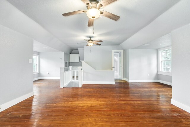 unfurnished living room featuring a ceiling fan, vaulted ceiling, dark wood-style floors, and a wealth of natural light