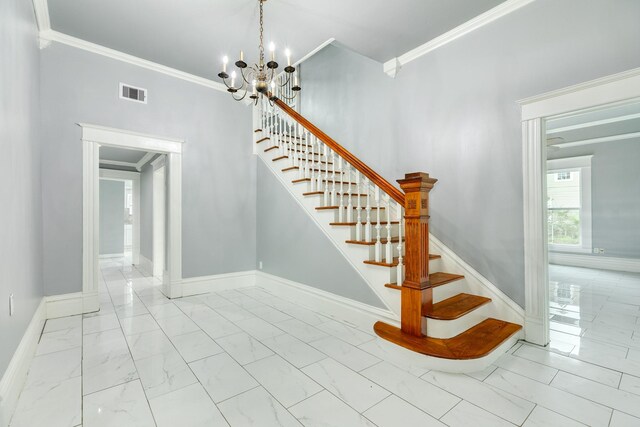 stairway featuring a notable chandelier, marble finish floor, baseboards, visible vents, and ornamental molding