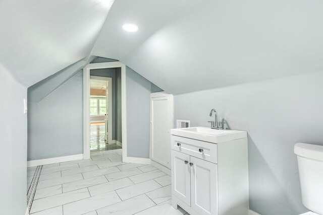 half bathroom featuring vanity, marble finish floor, lofted ceiling, toilet, and baseboards