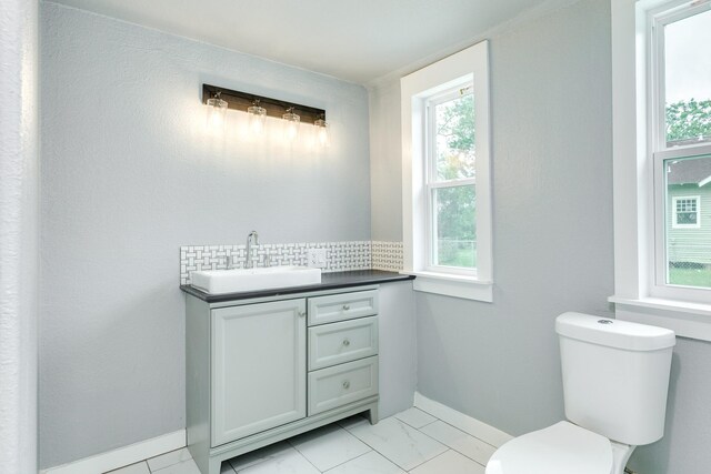 bathroom featuring vanity, toilet, marble finish floor, baseboards, and tasteful backsplash