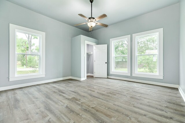 unfurnished bedroom with baseboards, multiple windows, and wood finished floors