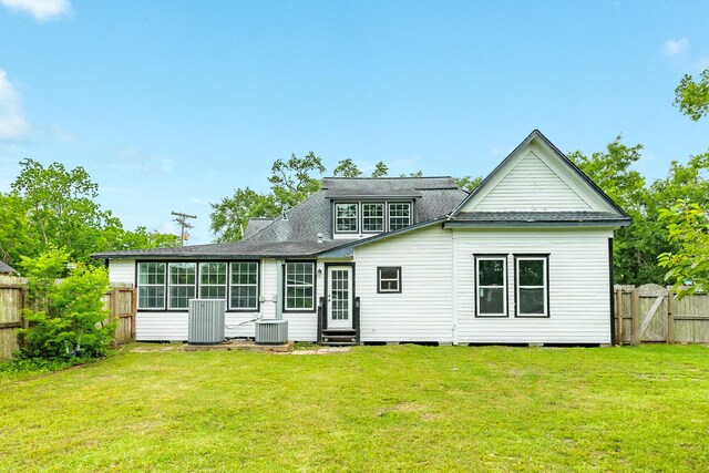 back of house with a lawn, central AC unit, a fenced backyard, and entry steps