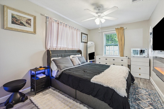 bedroom with baseboards, a ceiling fan, a textured ceiling, and wood finished floors