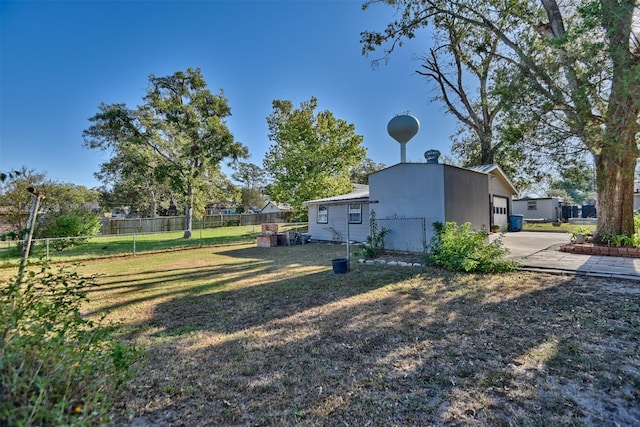 view of yard with an attached garage, fence, and driveway