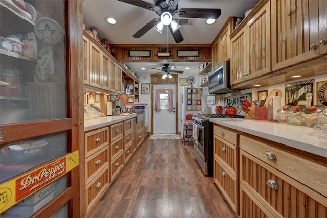 kitchen with ceiling fan, brown cabinetry, appliances with stainless steel finishes, dark wood finished floors, and light countertops