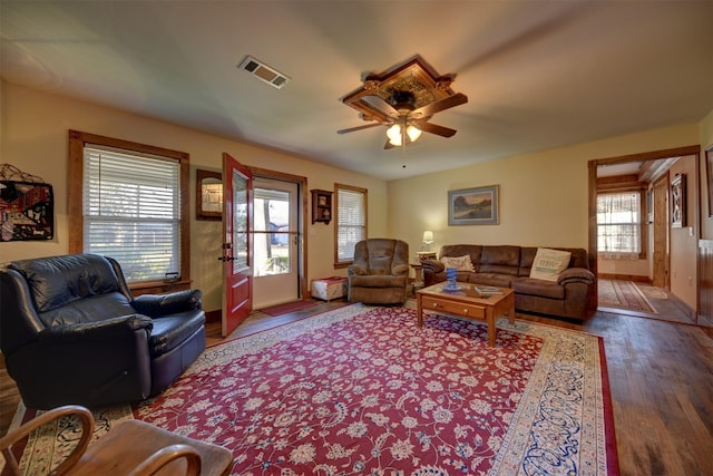 living area with ceiling fan, visible vents, and wood finished floors