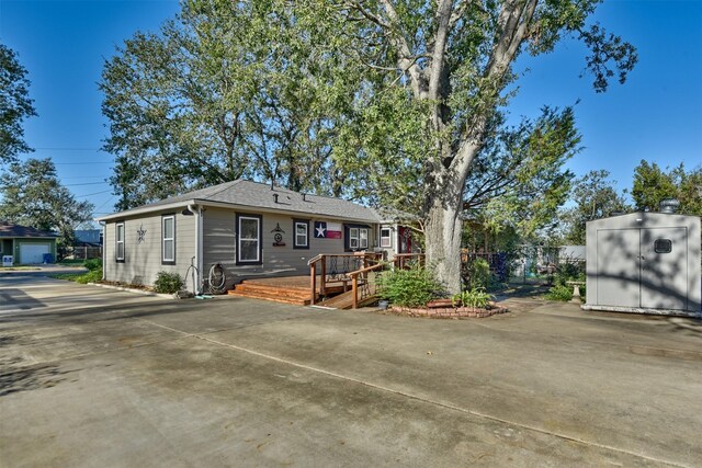 bungalow with a wooden deck, a storage unit, and an outdoor structure