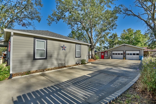 view of property exterior featuring a shingled roof, an outdoor structure, and a garage