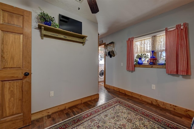 unfurnished room with stacked washer / dryer, baseboards, ceiling fan, and hardwood / wood-style floors