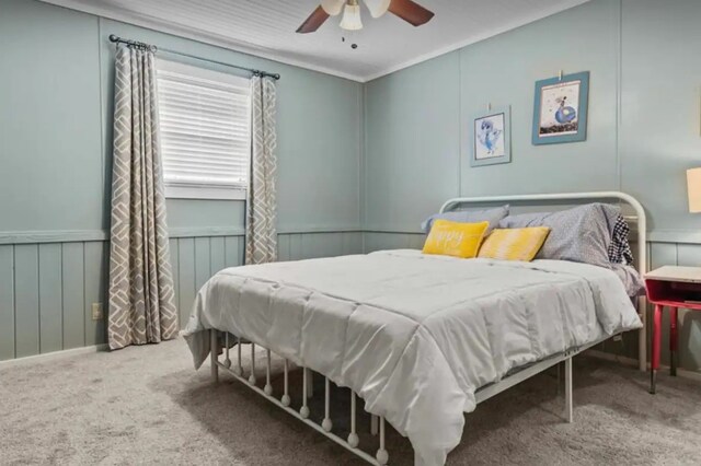 carpeted bedroom featuring ceiling fan and a decorative wall