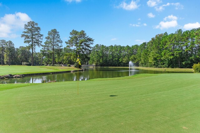 view of home's community featuring a lawn, a water view, and golf course view