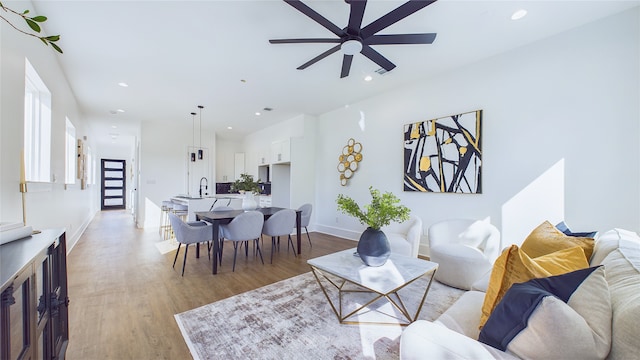 living area featuring recessed lighting, ceiling fan, baseboards, and light wood-style floors