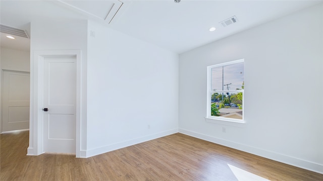 empty room featuring baseboards, visible vents, wood finished floors, and attic access