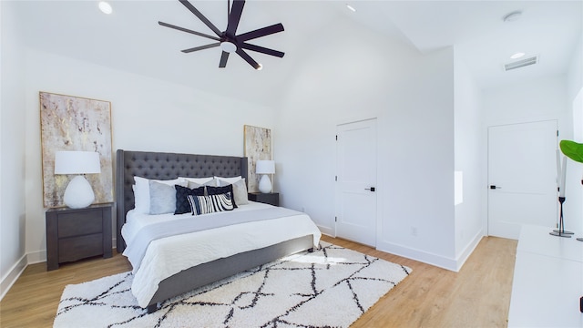 bedroom featuring visible vents, light wood finished floors, baseboards, and high vaulted ceiling