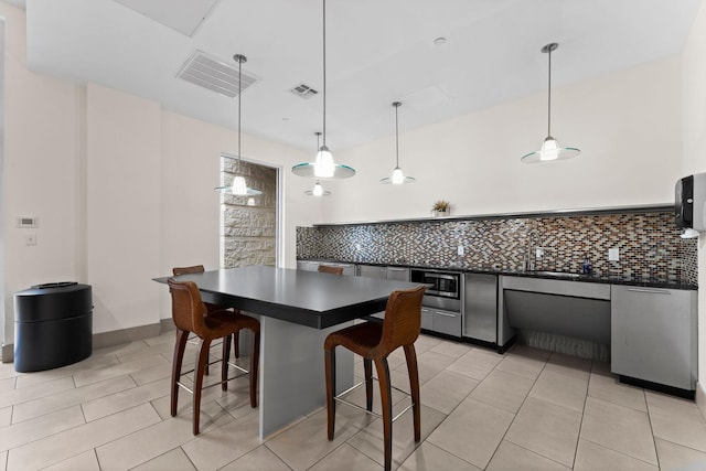 kitchen featuring visible vents, backsplash, dark countertops, and a kitchen bar