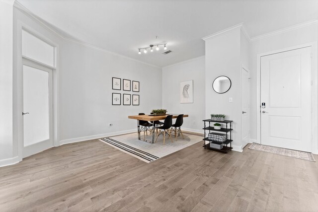 dining area featuring baseboards, ornamental molding, light wood finished floors, and visible vents