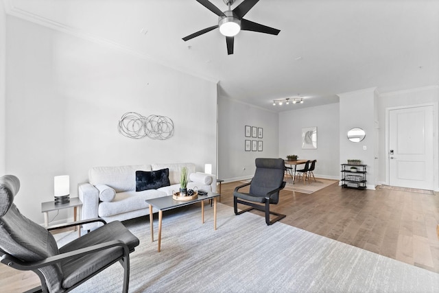 living room featuring crown molding, ceiling fan, baseboards, and wood finished floors