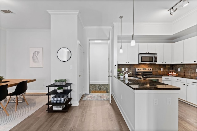 kitchen with appliances with stainless steel finishes, white cabinetry, a peninsula, wood finished floors, and visible vents