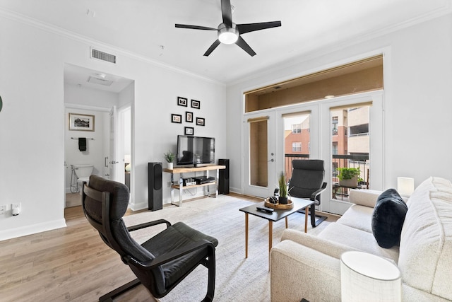 living room featuring ceiling fan, visible vents, wood finished floors, baseboards, and ornamental molding
