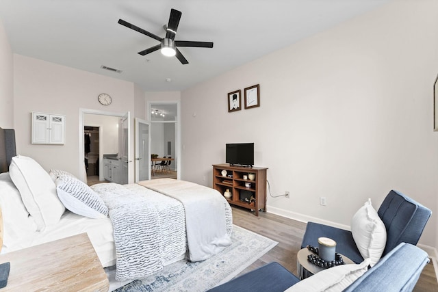 bedroom with a spacious closet, baseboards, wood finished floors, and visible vents