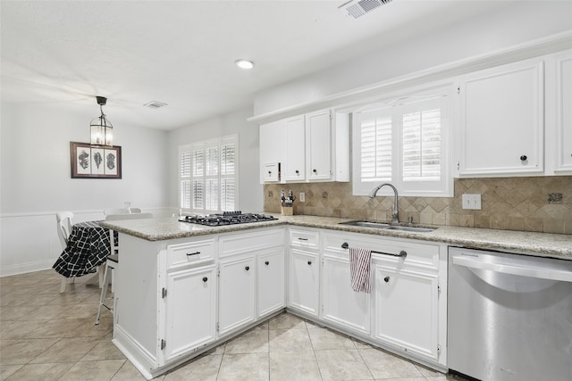 kitchen featuring stainless steel dishwasher, black gas stovetop, a sink, and a healthy amount of sunlight