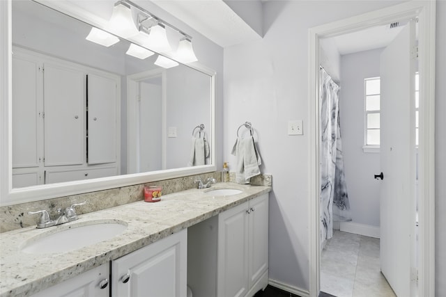 full bathroom with double vanity, baseboards, a sink, and tile patterned flooring