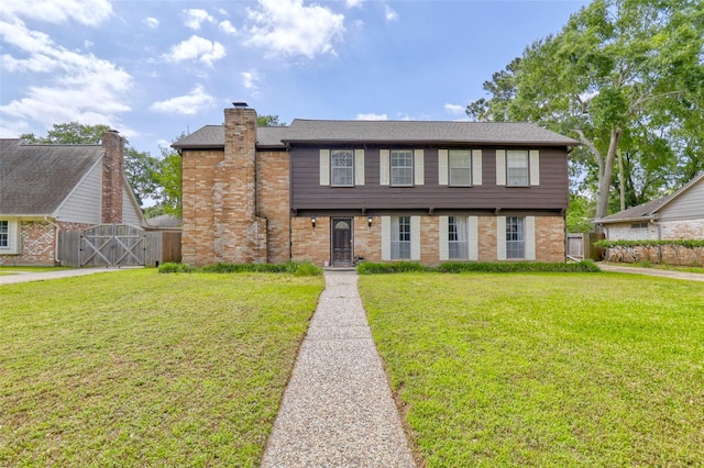 colonial inspired home with fence, a gate, a front yard, and brick siding