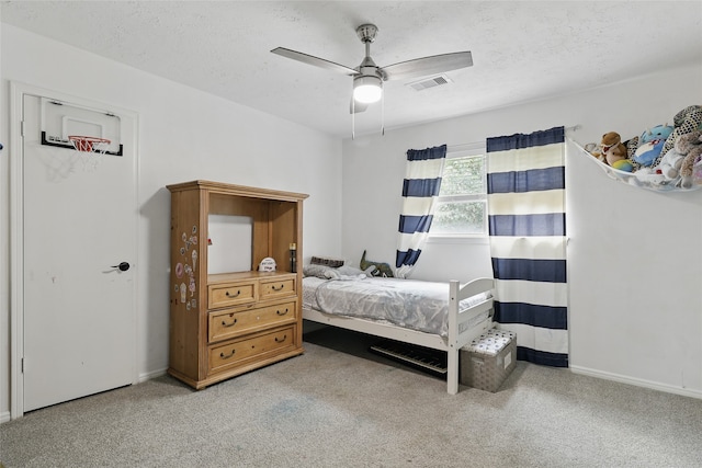 bedroom with carpet floors, a textured ceiling, a ceiling fan, baseboards, and visible vents