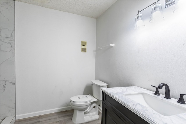 bathroom featuring vanity, a textured ceiling, toilet, and wood finished floors