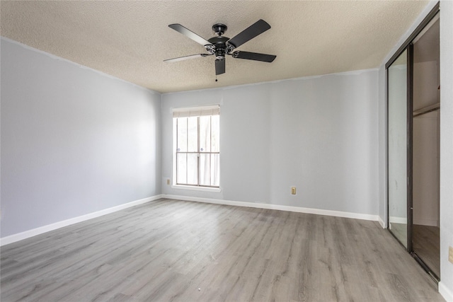 unfurnished bedroom with a closet, a textured ceiling, baseboards, and light wood-style floors