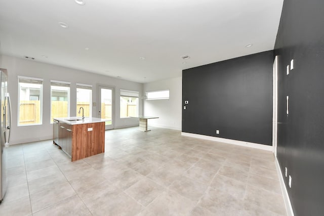 kitchen with light countertops, appliances with stainless steel finishes, a center island with sink, and open floor plan