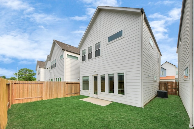 rear view of house with a fenced backyard, central air condition unit, and a yard
