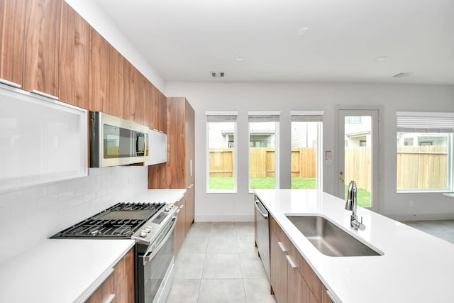 kitchen featuring a sink, modern cabinets, brown cabinetry, and stainless steel appliances